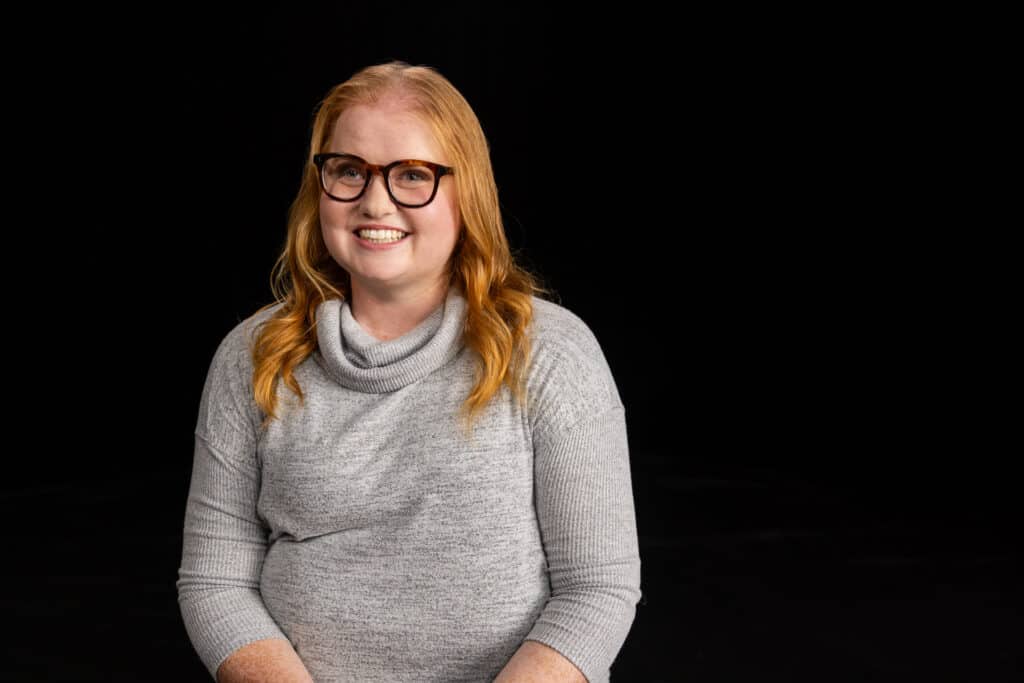 Georgia Pike sits wearing glasses and a grey turtleneck sweater.