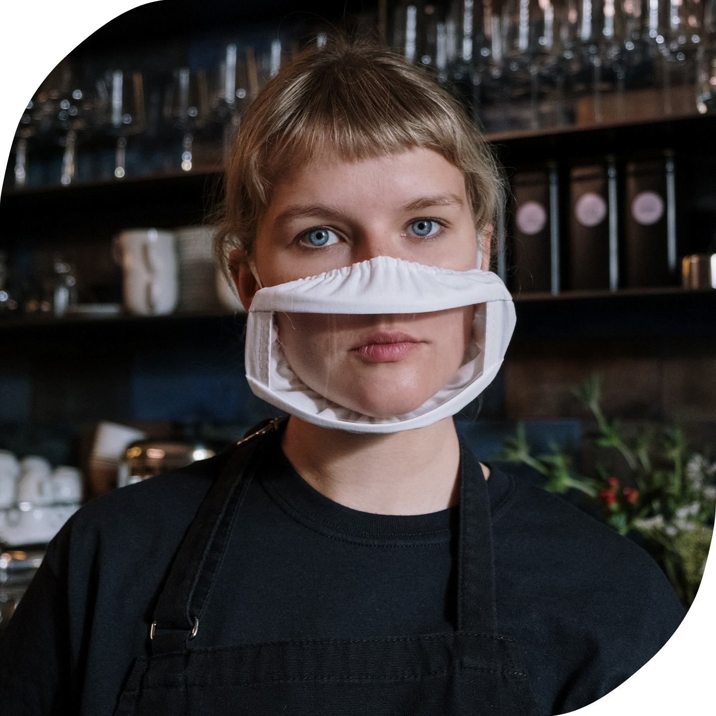 A white person who is deaf and wearing a clear mask working at a bar