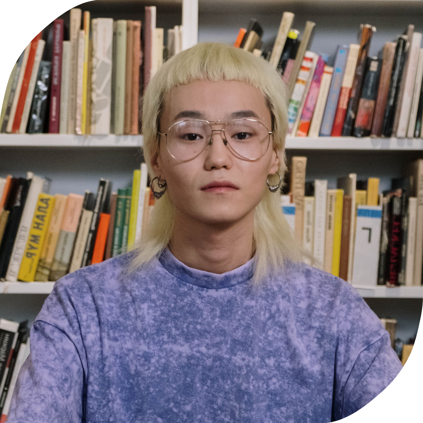 A portrait of a trans Asian person with blonde hair in a library