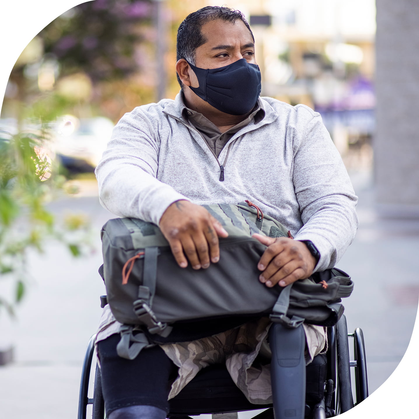 A Hispanic man wearing a black mask and sitting in a wheelchair.