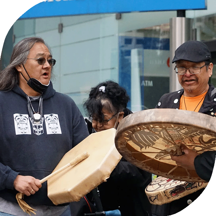 Maxwell Johnson (left) joins other Heiltsuk First Nation members in ceremony outside the Burrard Street BMO branch in Vancouver on May 5, 2022.
