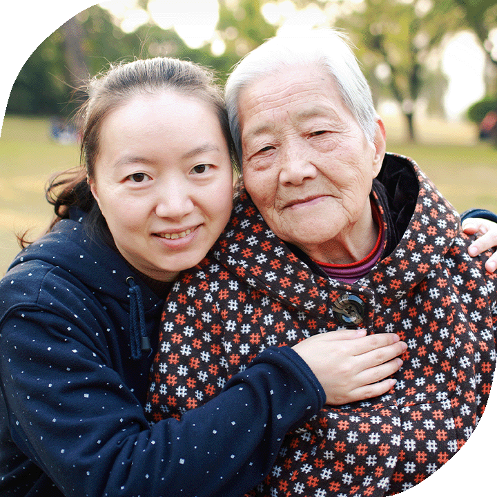 A young Asian woman embraces her grandmother.