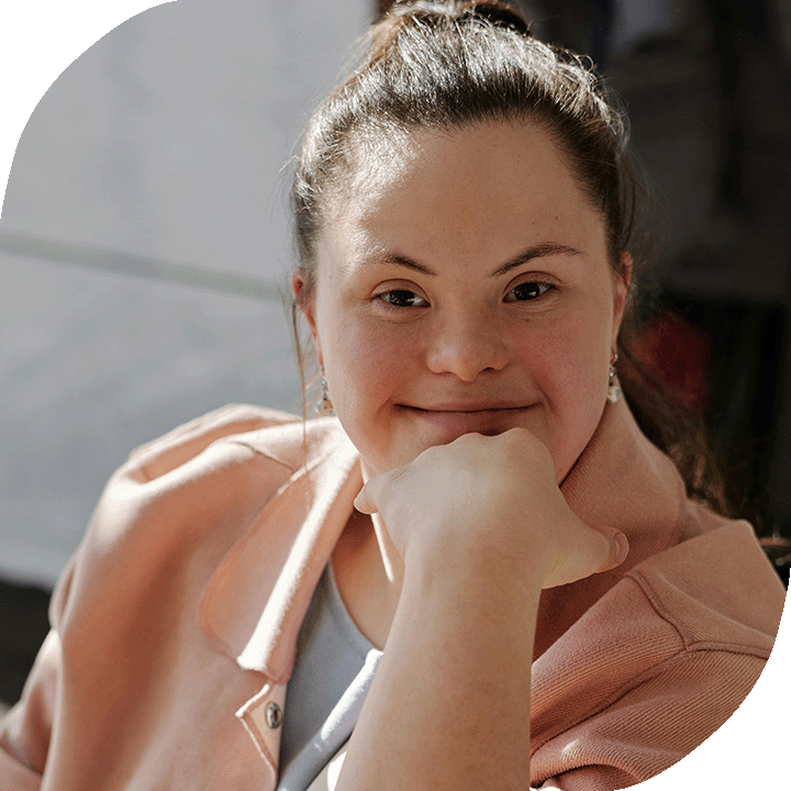 A young woman with Down syndrome smiles confidently.